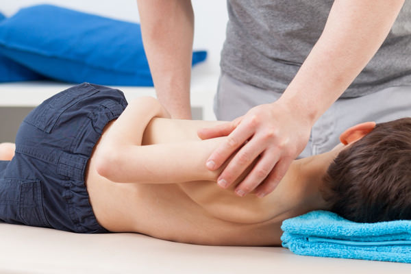 Physiotherapist stretching body of little patient - panorama